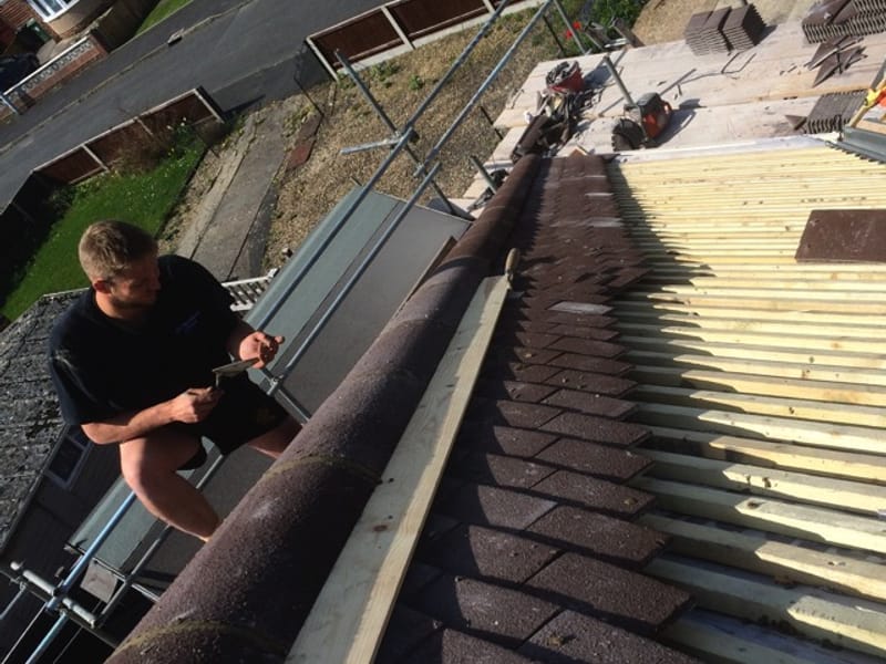 Roofer installing a Velux window on a slate roof in Gloucestershire